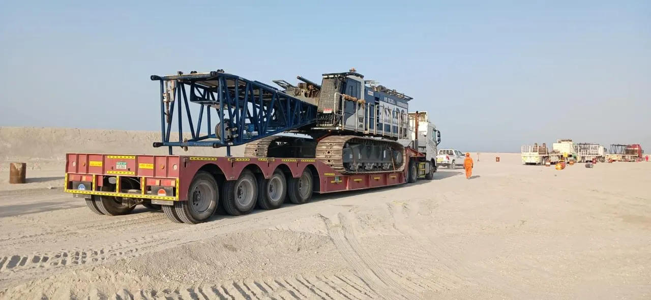 Crawler crane with lattice boom sections loaded on a multi-axle low-bed trailer