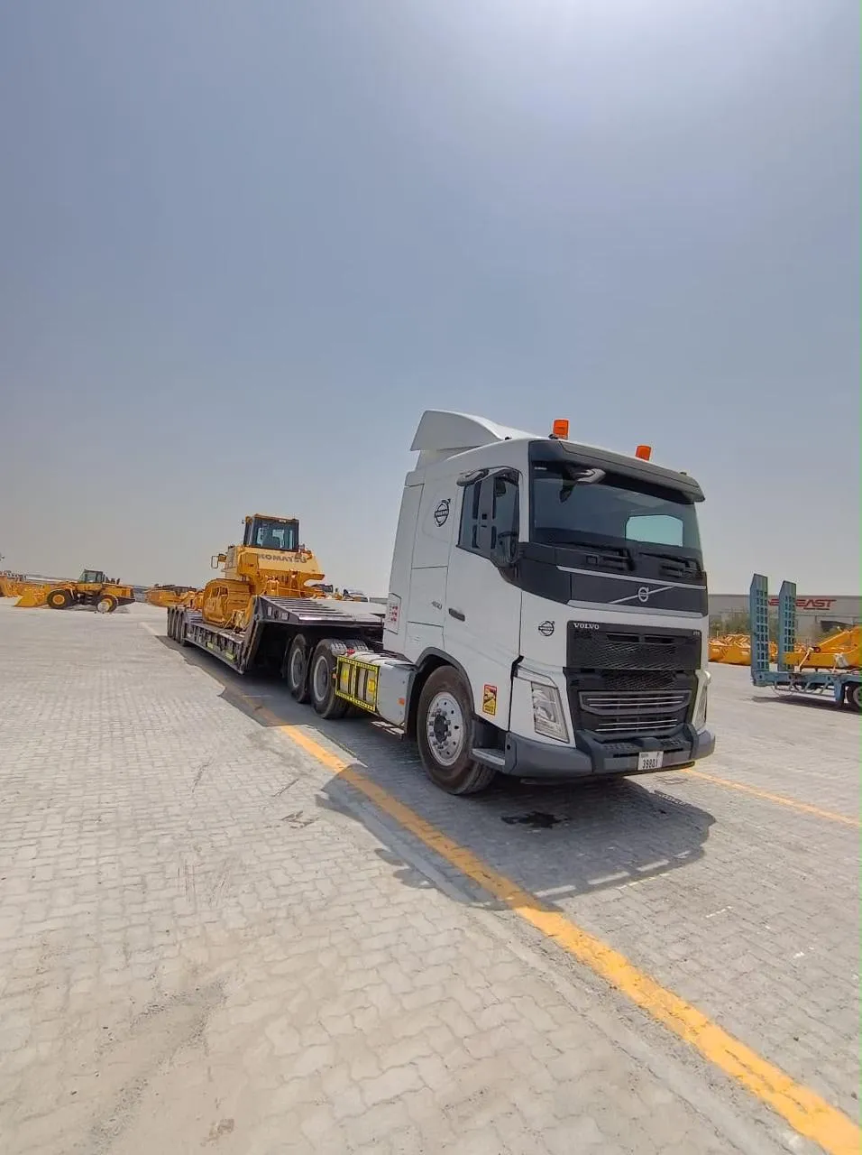 Komatsu tracked dozer loaded on a low-bed trailer pulled by a Volvo prime mover